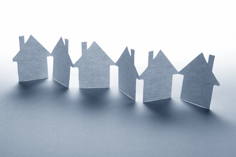 close up of houses cut out of paper on white background